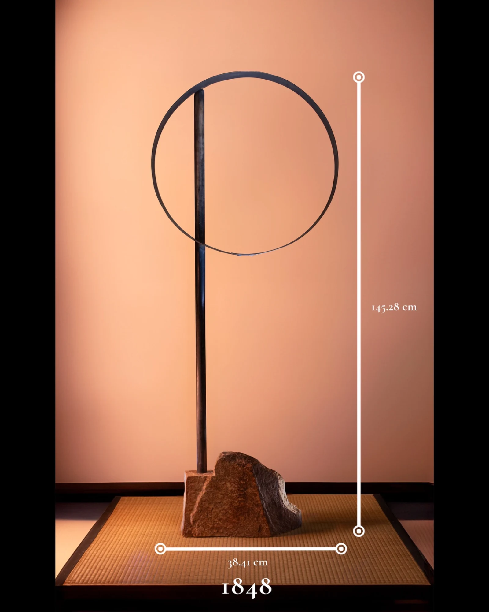 1848, a tall minimalist sculpture composed of a stone base, dark vertical steel support, and circular steel hoop.